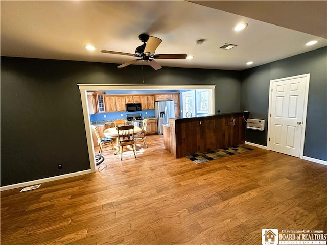 kitchen featuring light wood finished floors, visible vents, a peninsula, stainless steel appliances, and a ceiling fan