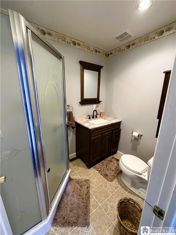 bathroom with vanity, baseboards, visible vents, a stall shower, and toilet