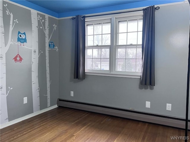 spare room with baseboard heating, baseboards, and wood finished floors