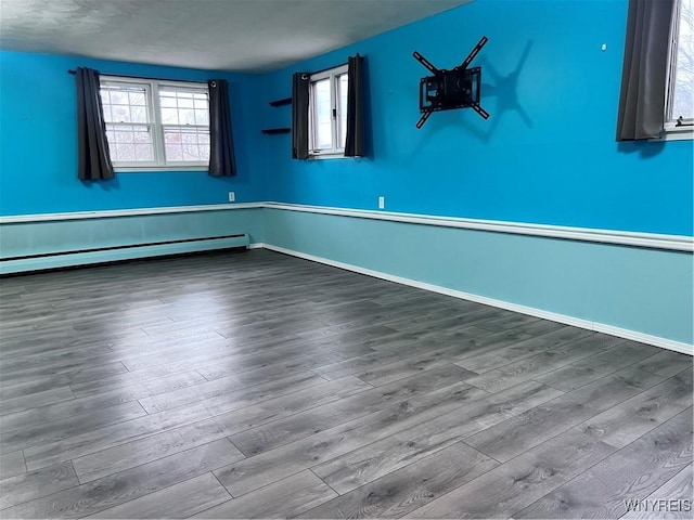 spare room featuring wood finished floors, baseboards, and a baseboard radiator