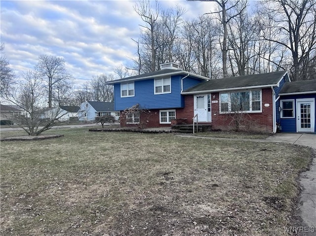 tri-level home with brick siding and a front yard