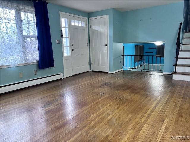 foyer featuring plenty of natural light, a baseboard heating unit, stairs, and hardwood / wood-style flooring