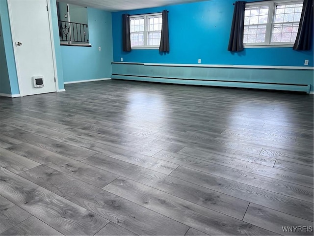 unfurnished room with dark wood finished floors, baseboards, and a baseboard radiator