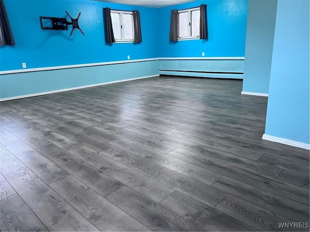 spare room featuring dark wood-style floors, baseboards, and a baseboard radiator