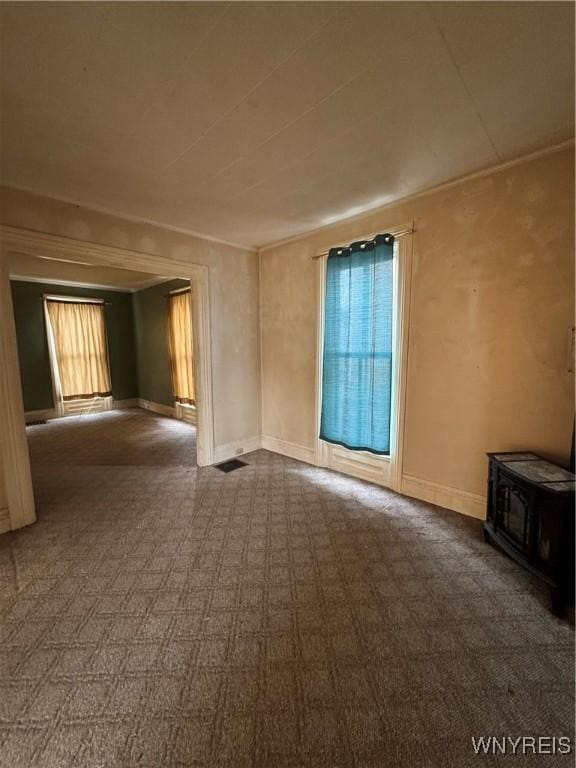 unfurnished living room featuring baseboards and a wood stove