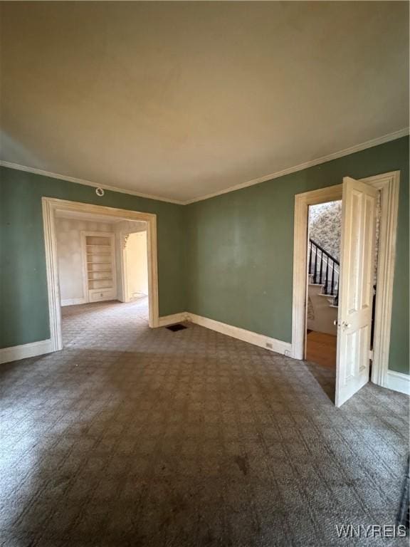 unfurnished room featuring baseboards, visible vents, and ornamental molding