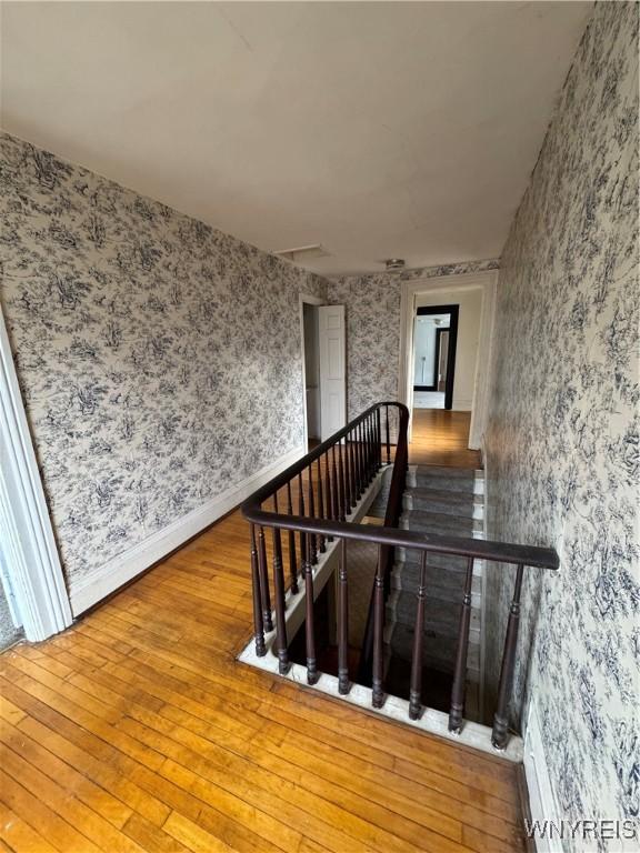 staircase with baseboards, attic access, hardwood / wood-style floors, and wallpapered walls