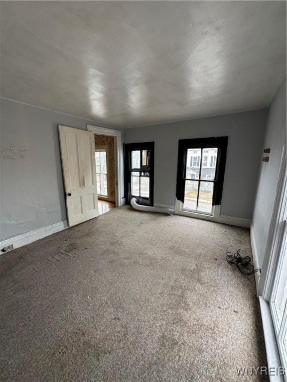 empty room featuring baseboards, a healthy amount of sunlight, and carpet flooring