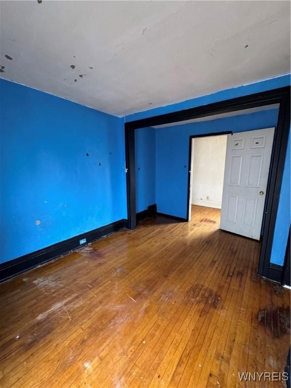 spare room featuring hardwood / wood-style flooring and baseboards