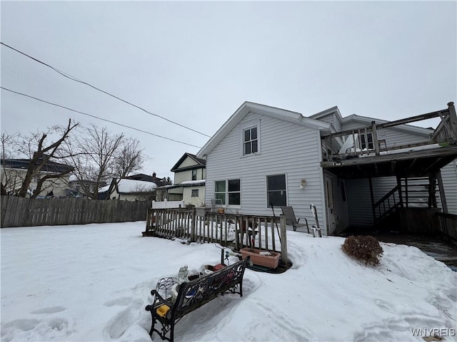 snow covered property with stairway, a deck, and fence