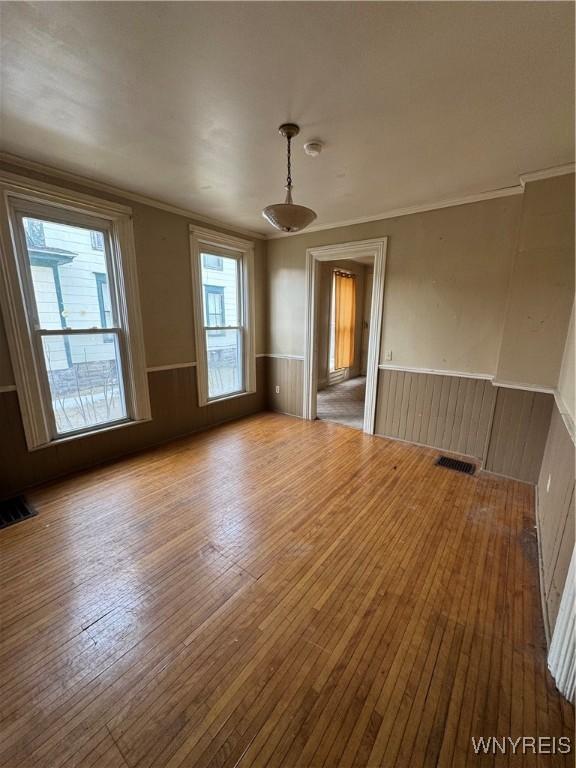 spare room featuring visible vents, wainscoting, and wood-type flooring