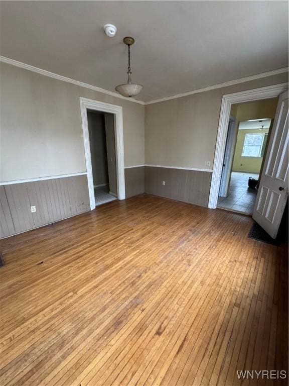 spare room featuring a wainscoted wall, hardwood / wood-style floors, and crown molding