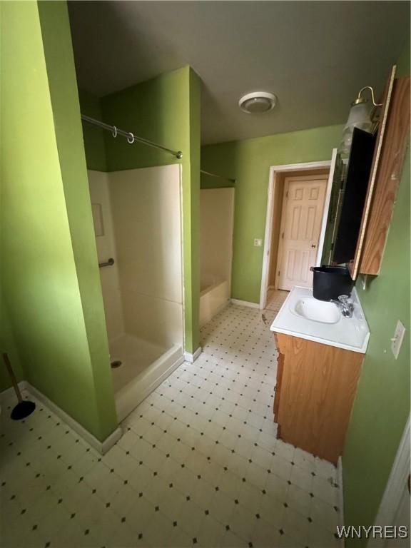 bathroom with baseboards, walk in shower, a washtub, tile patterned floors, and vanity