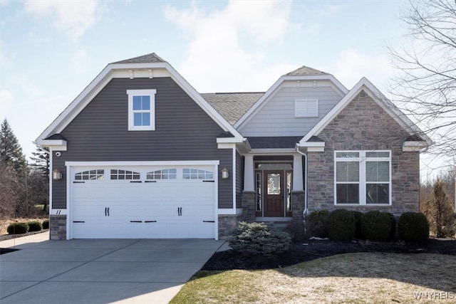 craftsman-style house featuring a garage, stone siding, driveway, and roof with shingles