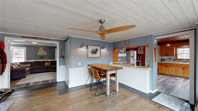 kitchen with wood ceiling, a healthy amount of sunlight, freestanding refrigerator, and wainscoting