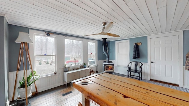 dining room featuring a healthy amount of sunlight, wainscoting, and a wood stove