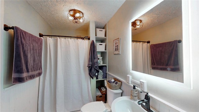 bathroom featuring curtained shower, a textured ceiling, and toilet