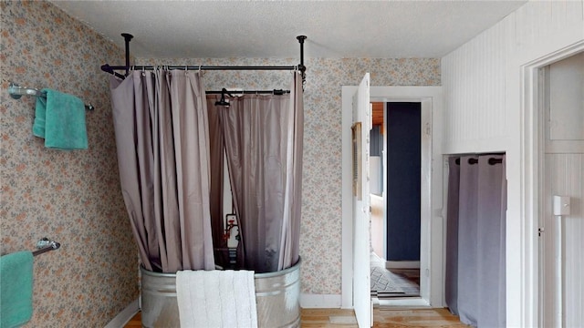 bathroom featuring curtained shower, a textured ceiling, wood finished floors, and wallpapered walls