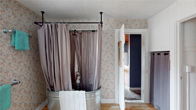 bathroom featuring curtained shower, wood finished floors, and wallpapered walls