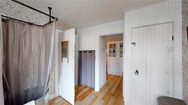 interior space with a shower with shower curtain, a textured ceiling, and wood finished floors