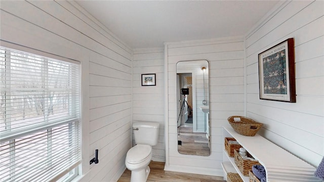 bathroom featuring ornamental molding, a healthy amount of sunlight, toilet, and wood finished floors