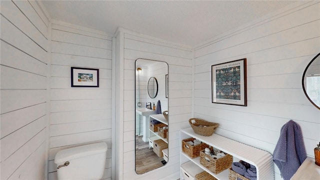 bathroom featuring wooden walls and toilet