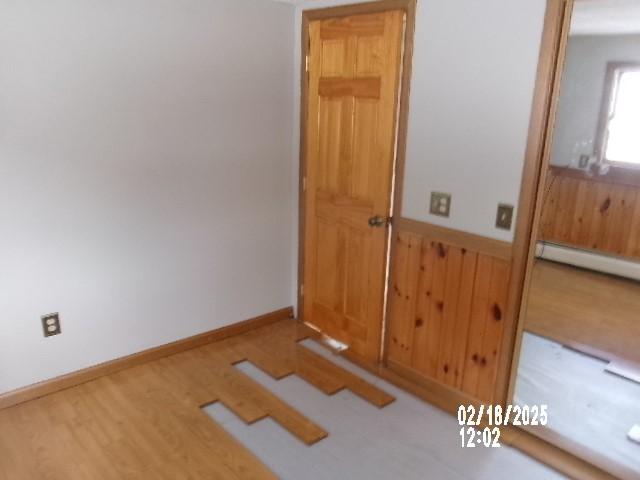 153 Holden Rd, Southport, NY 14871 - spare room with a baseboard heating unit, wooden walls, wood finished floors, and wainscoting