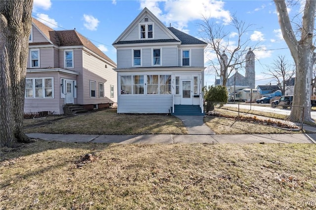 view of front facade featuring a sunroom, fence, a front yard, and entry steps