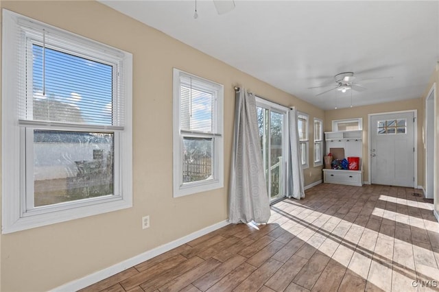 interior space with baseboards, wood finished floors, and a ceiling fan