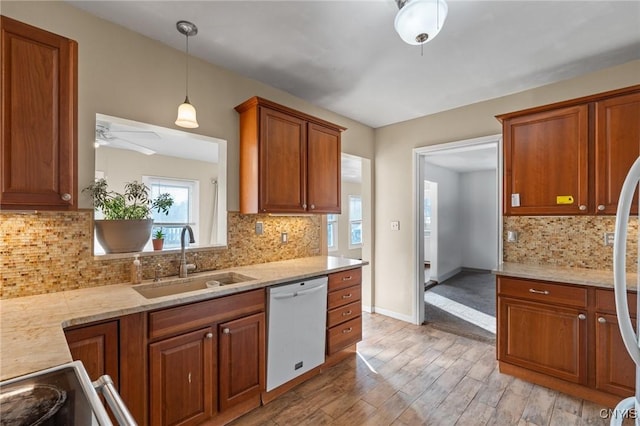 kitchen with ceiling fan, brown cabinets, light wood-style floors, white dishwasher, and a sink