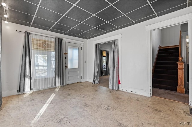 unfurnished room with stairs, baseboards, and a drop ceiling