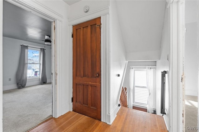 corridor with carpet flooring, an upstairs landing, and baseboards