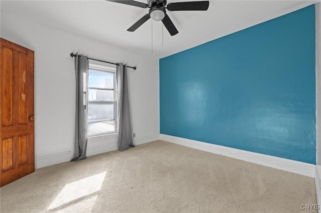 carpeted spare room featuring baseboards and ceiling fan