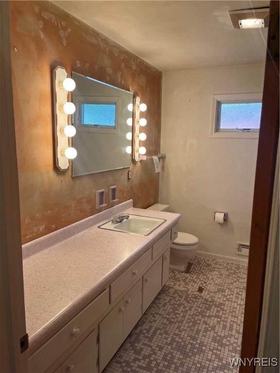 bathroom featuring toilet, vanity, and baseboards