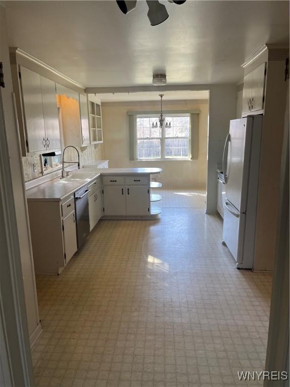 kitchen featuring light floors, light countertops, freestanding refrigerator, and stainless steel dishwasher