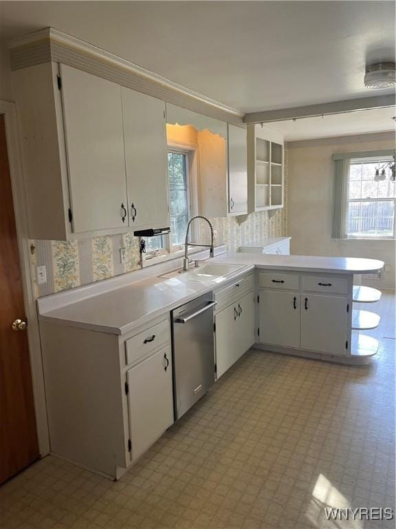 kitchen featuring stainless steel dishwasher, light floors, and light countertops