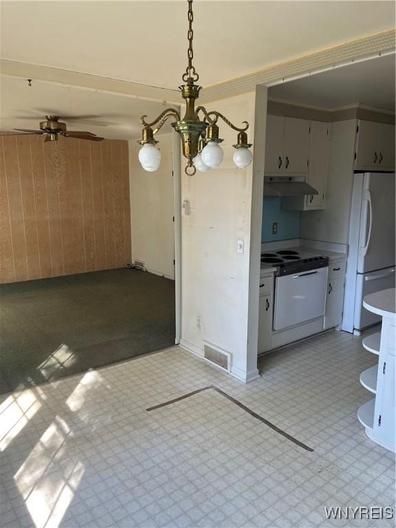 kitchen featuring visible vents, freestanding refrigerator, under cabinet range hood, wood walls, and tile patterned floors