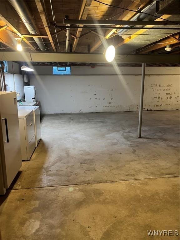 unfinished basement featuring washing machine and clothes dryer and refrigerator