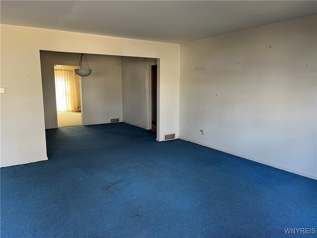 unfurnished room featuring dark colored carpet, visible vents, and baseboards