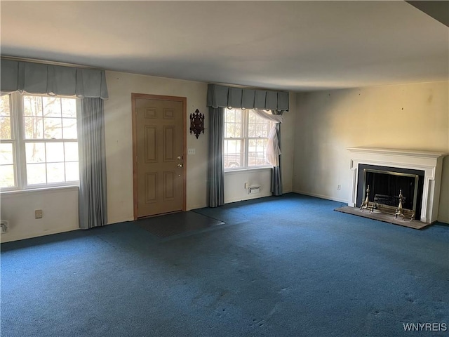 unfurnished living room featuring carpet flooring and a fireplace with raised hearth