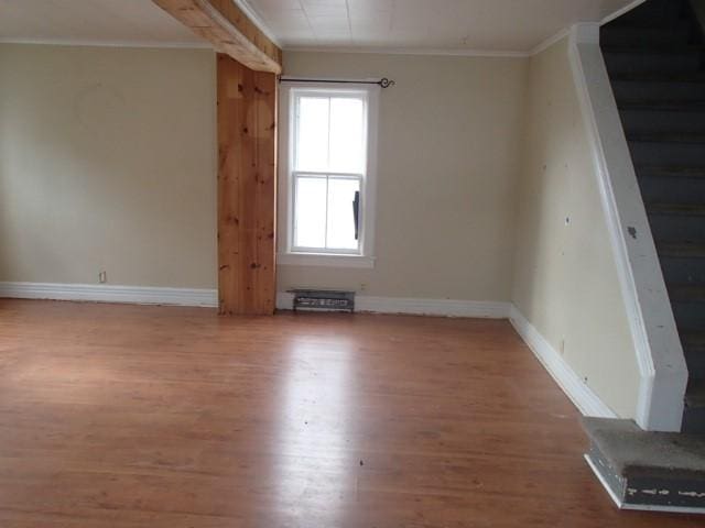 unfurnished room with baseboards, wood finished floors, ornamental molding, and stairs