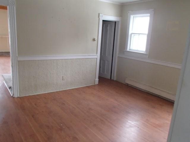 spare room with a baseboard radiator and wood finished floors