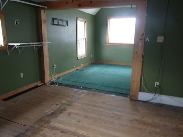 unfurnished room with lofted ceiling, baseboards, and wood-type flooring