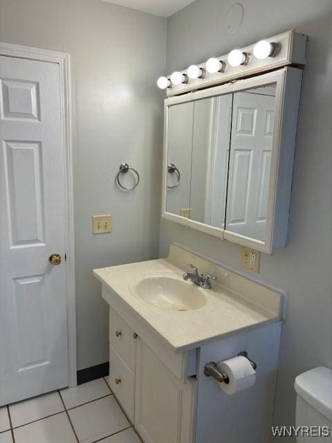 half bath featuring tile patterned floors, toilet, and vanity