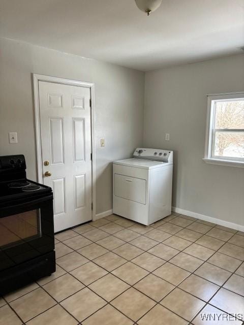 clothes washing area with light tile patterned flooring, laundry area, washer / dryer, and baseboards