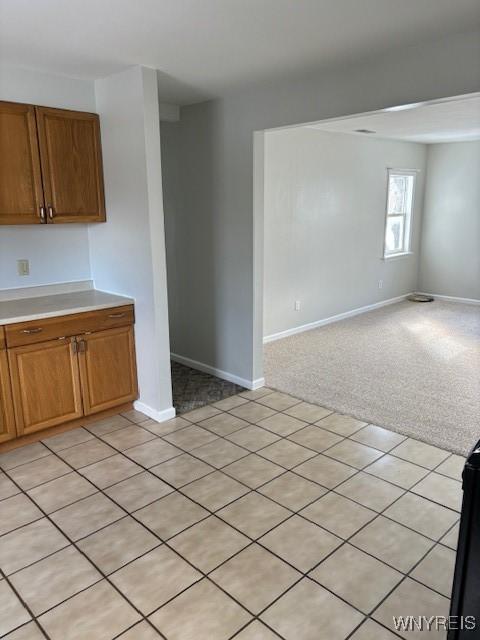 interior space featuring light countertops, light colored carpet, open floor plan, and baseboards