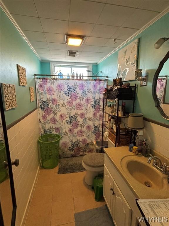 bathroom featuring tile patterned floors, a wainscoted wall, curtained shower, and ornamental molding