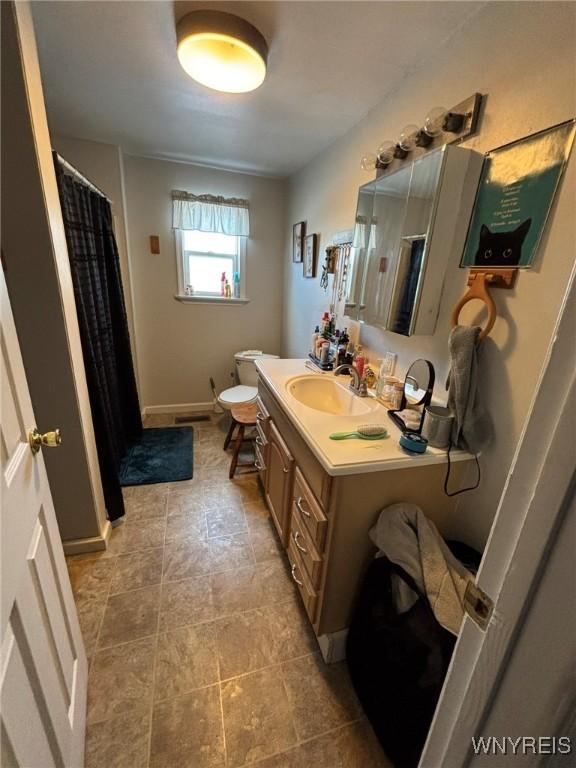 full bathroom featuring toilet, vanity, a shower with shower curtain, and baseboards