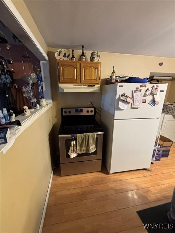 kitchen with brown cabinetry, light wood finished floors, freestanding refrigerator, stainless steel range with electric stovetop, and under cabinet range hood