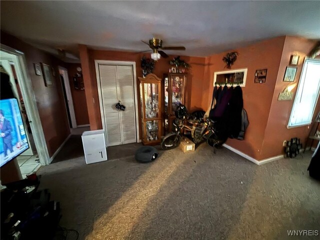 interior space featuring carpet flooring, baseboards, and ceiling fan